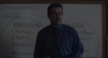 Movie still from “Boy Erased” (2018), directed by Joel Edgerton – A man standing in front of a white board; Medium shot, Over the shoulder angle