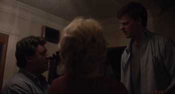 Movie still from “Boy Erased” (2018), directed by Joel Edgerton – Two men and a woman are talking to each other in a living room; Medium shot, Over the shoulder angle