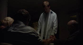 Movie still from “Boy Erased” (2018), directed by Joel Edgerton – A man standing next to another man in a dark room; Medium shot, Over the shoulder angle