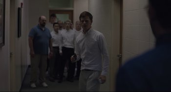 Movie still from “Boy Erased” (2018), directed by Joel Edgerton – A group of men standing in a hallway holding remotes; Wide shot, Over the shoulder angle