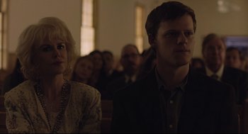 Movie still from “Boy Erased” (2018), directed by Joel Edgerton – A man and a woman are standing in front of a group of people; Close Up shot, Low angle