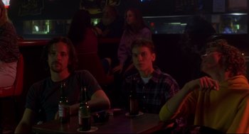 Movie still from “Boys Don't Cry” (1999), directed by Kimberly Peirce – A group of people sitting at a table with drinks; Medium shot, Over the shoulder angle