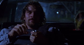 Movie still from “Boys Don't Cry” (1999), directed by Kimberly Peirce – A man sitting in the back seat of a car holding a steering wheel; Close Up shot, Over the shoulder angle