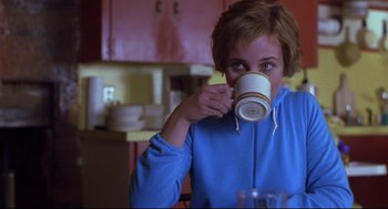 Movie still from “Boys Don't Cry” (1999), directed by Kimberly Peirce – A woman drinking a cup of coffee in a kitchen; Medium shot, Over the shoulder angle