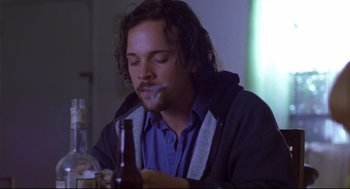 Movie still from “Boys Don't Cry” (1999), directed by Kimberly Peirce – A man sitting at a table holding a beer; Close Up shot, Low angle