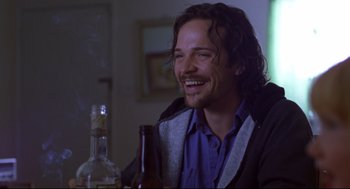 Movie still from “Boys Don't Cry” (1999), directed by Kimberly Peirce – A man sitting at a table with a bottle of beer; Close Up shot, Over the shoulder angle