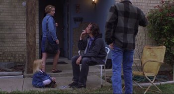 Movie still from “Boys Don't Cry” (1999), directed by Kimberly Peirce – A man sitting on a chair in front of a group of people; Wide shot, Over the shoulder angle