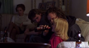 Movie still from “Boys Don't Cry” (1999), directed by Kimberly Peirce – A man and a girl are holding a bottle of soda; Medium shot, Over the shoulder angle