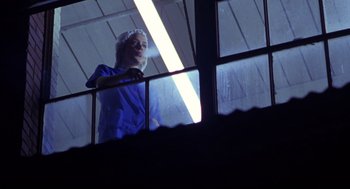 Movie still from “Boys Don't Cry” (1999), directed by Kimberly Peirce – A woman in a blue robe looking out of a window; Medium shot, Low angle