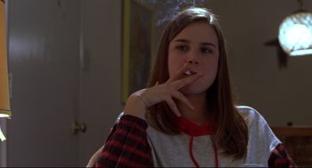 Movie still from “Boys Don't Cry” (1999), directed by Kimberly Peirce – A young woman smoking a cigarette while wearing a sweater; Medium shot, Low angle