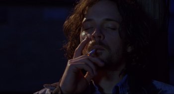 Movie still from “Boys Don't Cry” (1999), directed by Kimberly Peirce – A man with long hair is smoking a cigarette; Close Up shot, Low angle