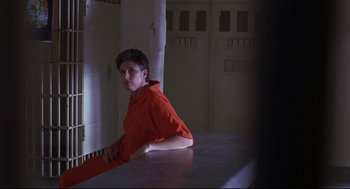 Movie still from “Boys Don't Cry” (1999), directed by Kimberly Peirce – A man sitting on top of a table in a jail cell; Medium shot, High angle