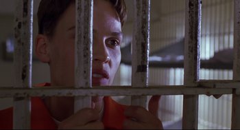 Movie still from “Boys Don't Cry” (1999), directed by Kimberly Peirce – A woman looking through bars of a jail cell; Close Up shot, Low angle