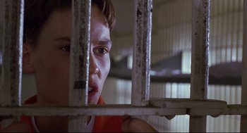 Movie still from “Boys Don't Cry” (1999), directed by Kimberly Peirce – A young boy looking through a metal fence; Close Up shot, Low angle