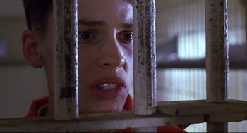 Movie still from “Boys Don't Cry” (1999), directed by Kimberly Peirce – A woman looking through the bars of a jail cell; Close Up shot, Low angle