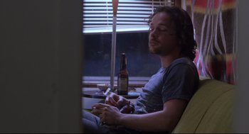 Movie still from “Boys Don't Cry” (1999), directed by Kimberly Peirce – A man sitting at a table in front of a beer bottle; Medium shot, Low angle