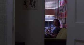 Movie still from “Boys Don't Cry” (1999), directed by Kimberly Peirce – A man sitting on a couch in front of a window; Wide shot, Over the shoulder angle