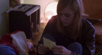 Movie still from “Boys Don't Cry” (1999), directed by Kimberly Peirce – A woman sitting on the floor looking at a piece of paper; Medium shot, High angle