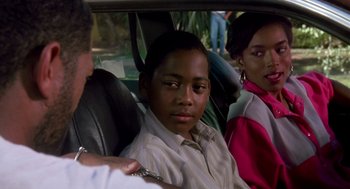 Movie still from “Boyz n the Hood” (1991), directed by John Singleton – Three people sitting in the back seat of a car; Close Up shot, Over the shoulder angle