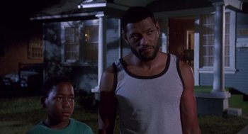 Movie still from “Boyz n the Hood” (1991), directed by John Singleton – A man standing next to a boy in front of a house; Medium shot, Over the shoulder angle