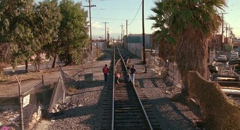 Movie still from “Boyz n the Hood” (1991), directed by John Singleton – Three people are standing on the railroad tracks; Extreme Wide shot, High angle