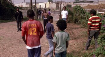 Movie still from “Boyz n the Hood” (1991), directed by John Singleton – A group of young men standing on top of a dirt field; Wide shot, High angle