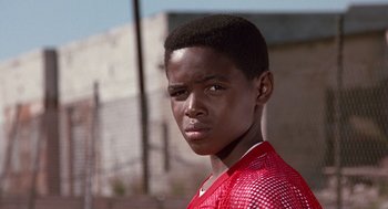 Movie still from “Boyz n the Hood” (1991), directed by John Singleton – A young man in a red shirt is looking at the camera; Close Up shot, Low angle