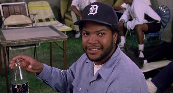 Movie still from “Boyz n the Hood” (1991), directed by John Singleton – A man wearing a baseball cap and a blue shirt; Medium shot, Low angle