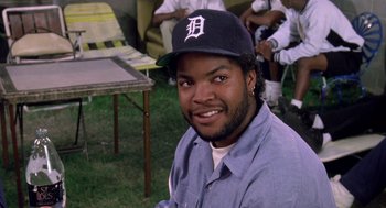 Movie still from “Boyz n the Hood” (1991), directed by John Singleton – A man with a baseball cap sitting in a field; Close Up shot, Over the shoulder angle