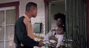 Movie still from “Boyz n the Hood” (1991), directed by John Singleton – An african american man holding a baby in front of a woman; Medium shot, Over the shoulder angle