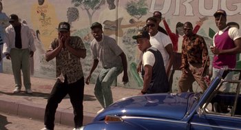 Movie still from “Boyz n the Hood” (1991), directed by John Singleton – A group of men standing next to each other on the street; Wide shot, High angle