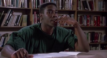 Movie still from “Boyz n the Hood” (1991), directed by John Singleton – A man sitting at a table in front of a book shelf; Close Up shot, High angle