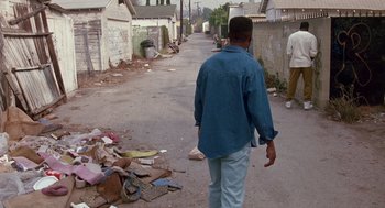 Movie still from “Boyz n the Hood” (1991), directed by John Singleton – A man walking down a street with a lot of trash on the ground; Wide shot, High angle