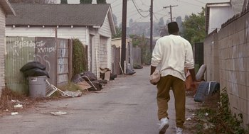Movie still from “Boyz n the Hood” (1991), directed by John Singleton – A man walking down the street with a hat on his head; Wide shot, High angle