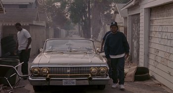 Movie still from “Boyz n the Hood” (1991), directed by John Singleton – A man standing in front of a car on a city street; Wide shot, High angle