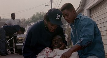 Movie still from “Boyz n the Hood” (1991), directed by John Singleton – Two men helping a man who is laying in a bed; Medium shot, High angle