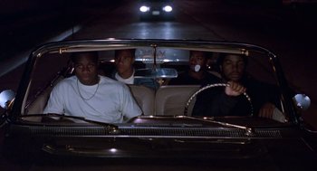 Movie still from “Boyz n the Hood” (1991), directed by John Singleton – A group of men riding in a car at night; Wide shot, High angle