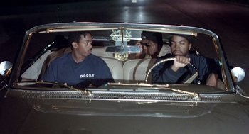 Movie still from “Boyz n the Hood” (1991), directed by John Singleton – A group of men sitting in the back seat of a car; Medium shot, Over the shoulder angle