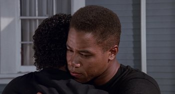 Movie still from “Boyz n the Hood” (1991), directed by John Singleton – A man and a woman hugging each other in front of a building; Close Up shot, Over the shoulder angle