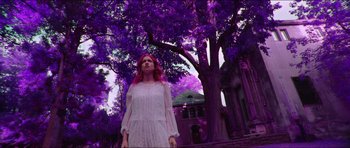 A woman standing in front of a purple tree