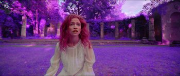 A woman with red hair standing in front of trees