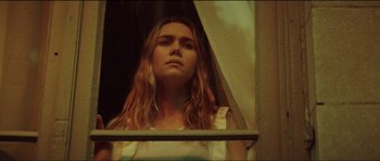 A woman standing in a window sill looking out of the window