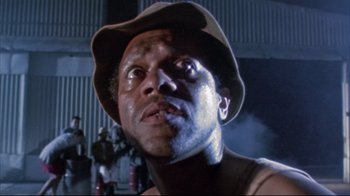 Movie still from “Dead Alive” (1992), directed by Peter Jackson – A person wearing a hat with smoke coming out of it; Close Up shot, Low angle