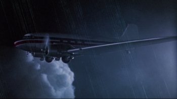 Movie still from “Dead Alive” (1992), directed by Peter Jackson – An airplane is flying in the dark sky; Extreme Wide shot, Low angle