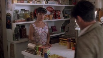Movie still from “Dead Alive” (1992), directed by Peter Jackson – A woman standing at a counter in a grocery store; Medium shot, Over the shoulder angle