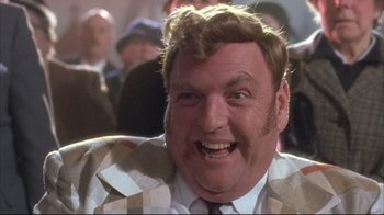 Movie still from “Dead Alive” (1992), directed by Peter Jackson – A person wearing a suit and tie; Close Up shot, Low angle