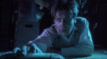 Movie still from “Dead Alive” (1992), directed by Peter Jackson – A man in a white shirt is looking at a computer screen; Close Up shot, Low angle