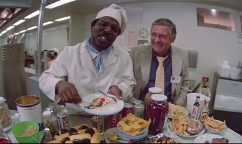 Movie still from “Brainstorm” (1983), directed by Douglas Trumbull – Two men sitting at a table with a plate of food; Medium shot, High angle