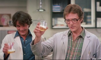 Movie still from “Brainstorm” (1983), directed by Douglas Trumbull – A man holding up a glass of beer in front of another man; Medium shot, Low angle