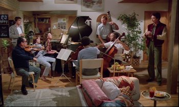 Movie still from “Brainstorm” (1983), directed by Douglas Trumbull – A group of people in a living room playing musical instruments; Wide shot, High angle